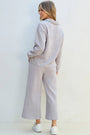 Woman wearing a light gray tracksuit against a white background