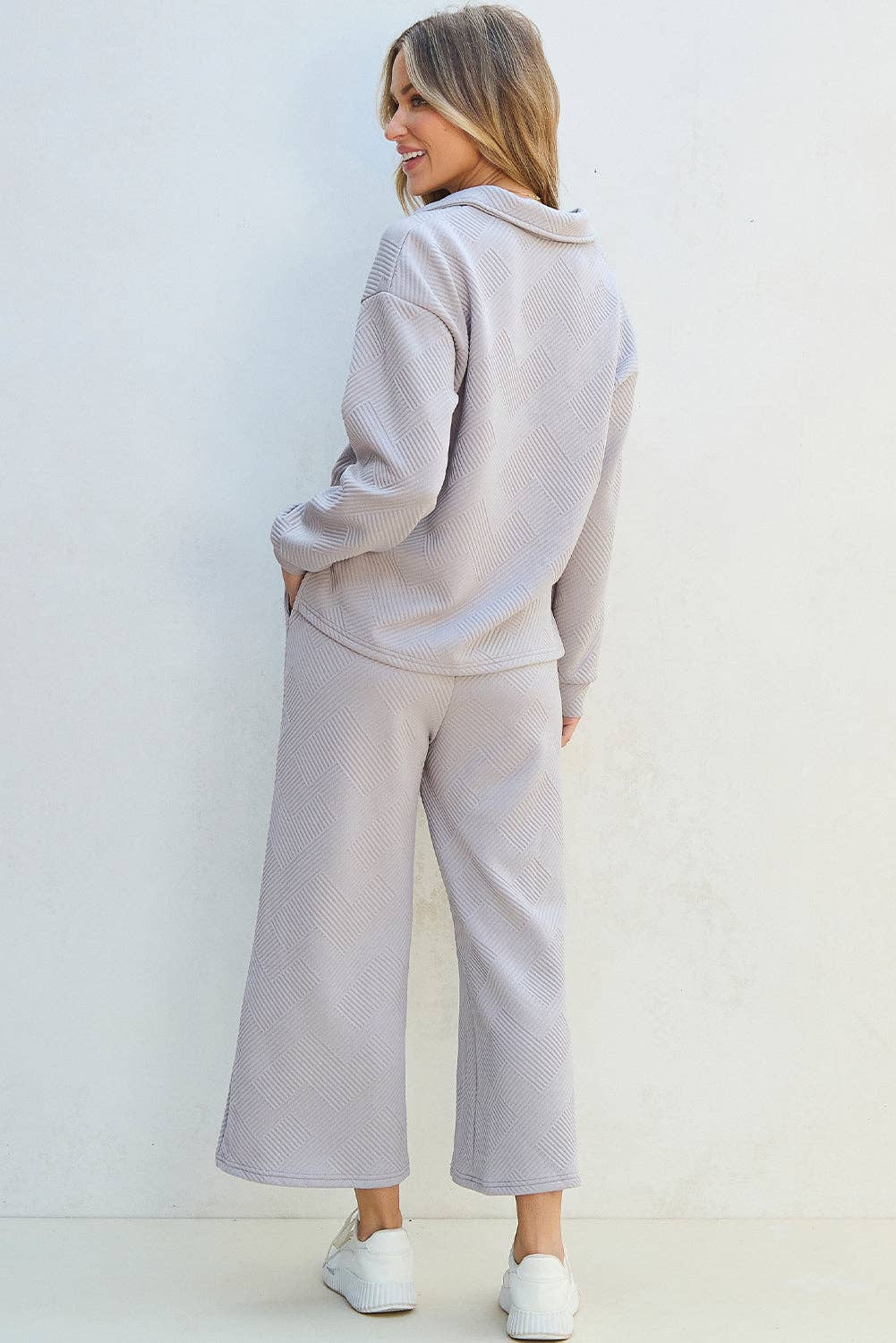 Woman wearing a light gray tracksuit against a white background