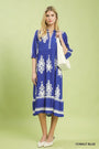 Woman wearing a cobalt blue dress with white patterns on a light green background
