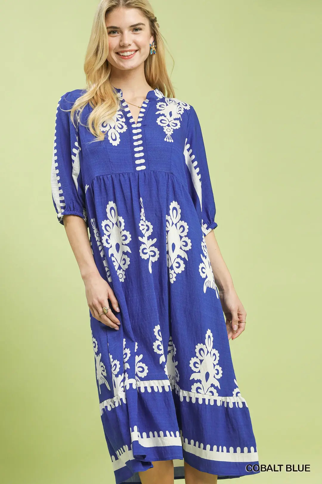 Woman wearing a blue dress with white patterns on a green background