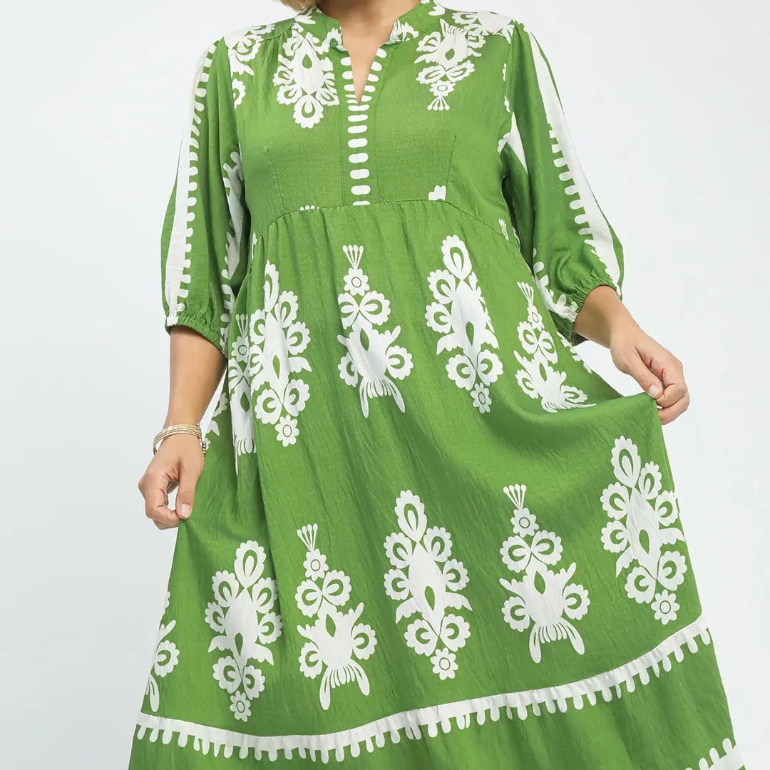 Green dress with white patterns on a model against a white background