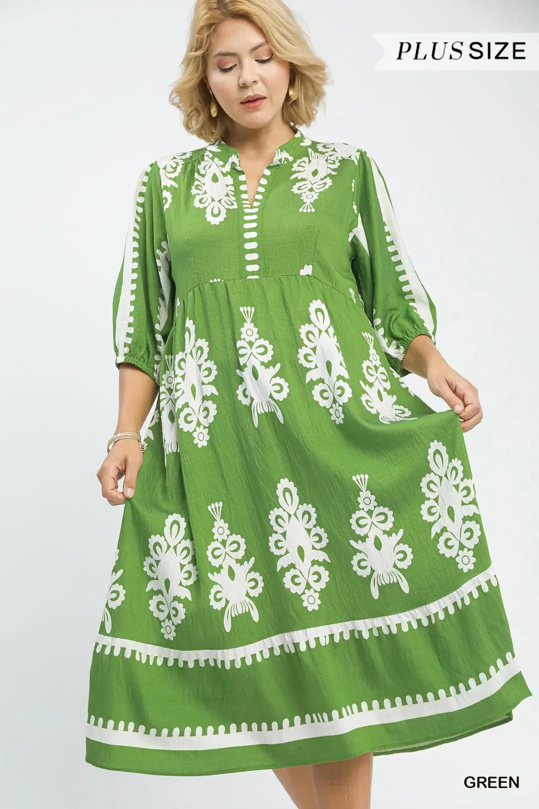 Green dress with white patterns on a model against a white background