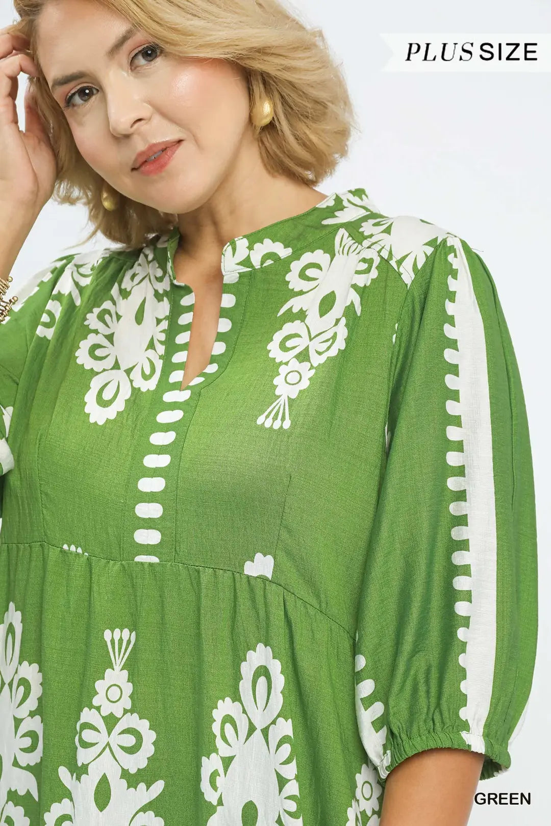 Woman wearing a green dress with white floral patterns on a white background