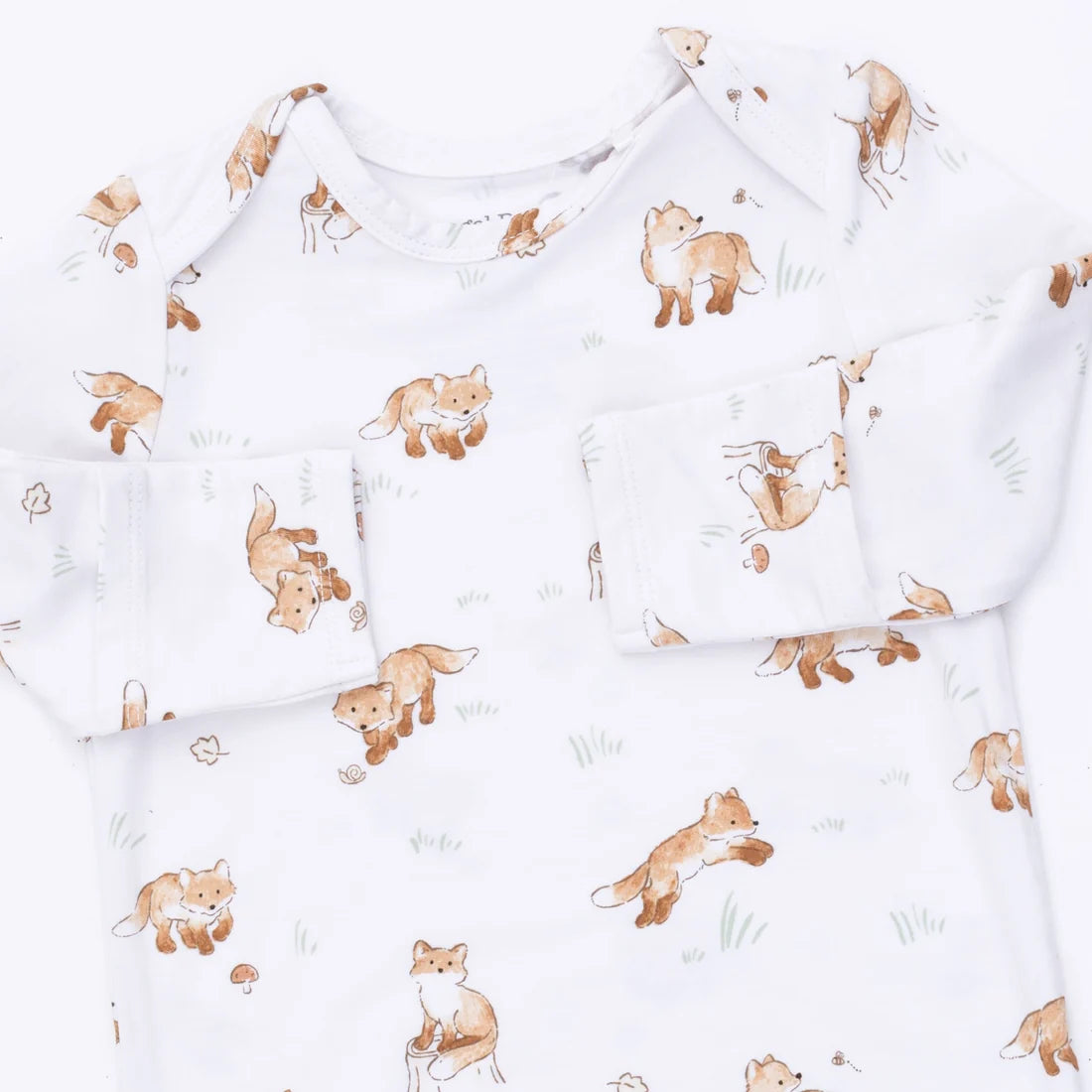 A white long-sleeve baby top with an all-over print of playful brown foxes and rabbits, featuring a chest pocket and shoulder snaps.