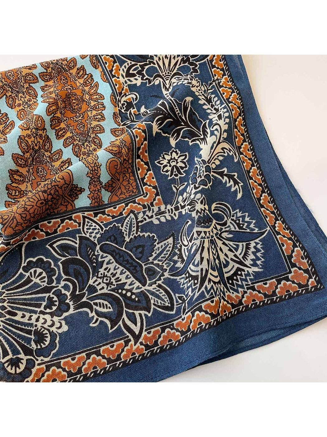 Close-up of navy retro floral square scarf with orange accents and intricate border