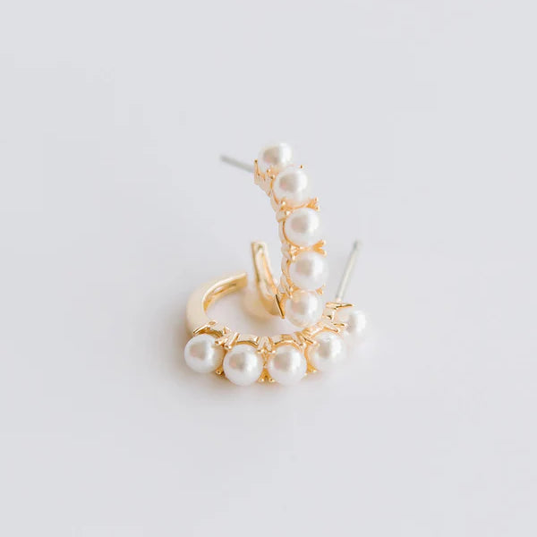 Gold earring with pearls on a light gray background