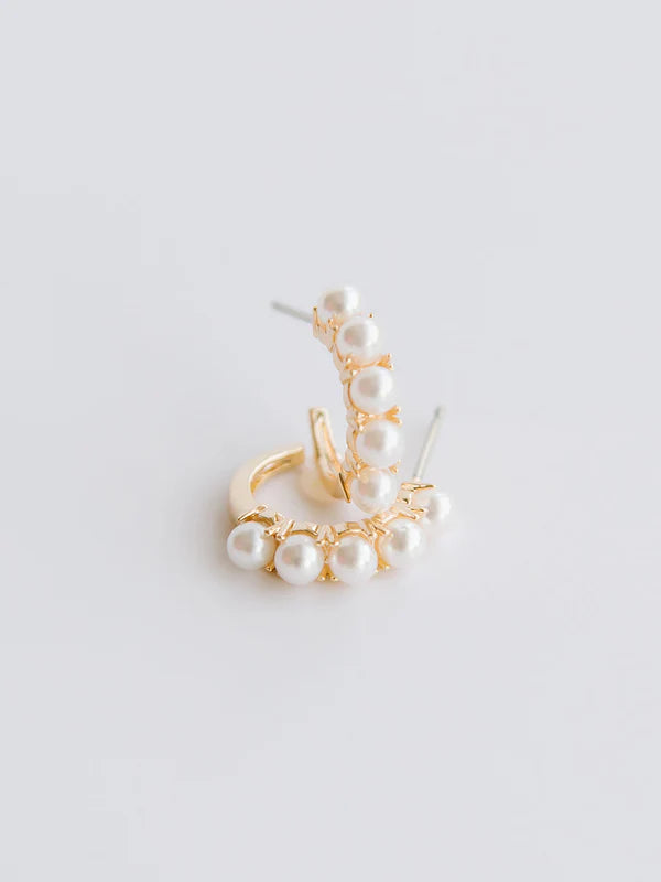 Gold earring with pearls on a light gray background