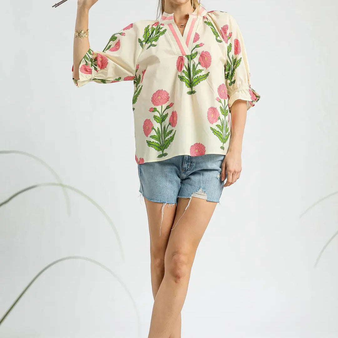Woman wearing a floral blouse and denim shorts holding flowers on a white background