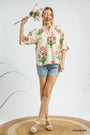 Woman wearing a floral blouse and denim shorts holding flowers on a white background