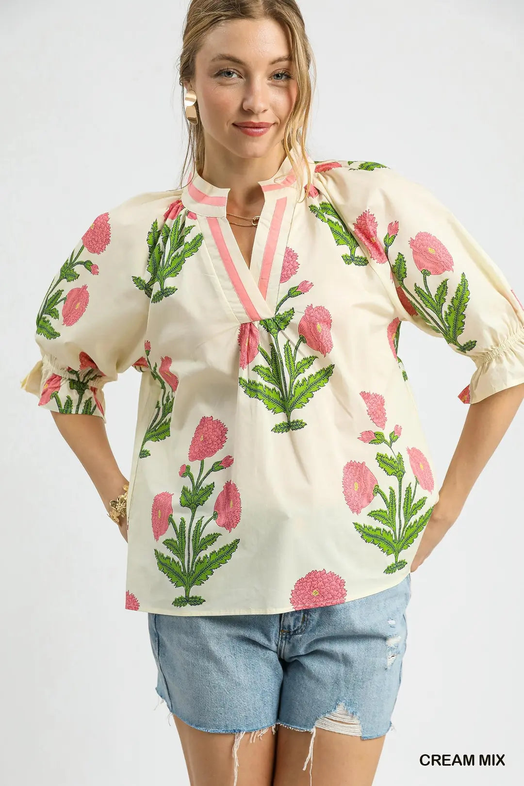 Woman wearing a floral blouse with pink flowers and green leaves on a white background