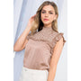 Woman wearing a patterned top with a plain background