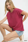 Woman wearing a berry-colored top and denim shorts on a white background