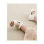 White sandal on a child's foot with a soft beige background