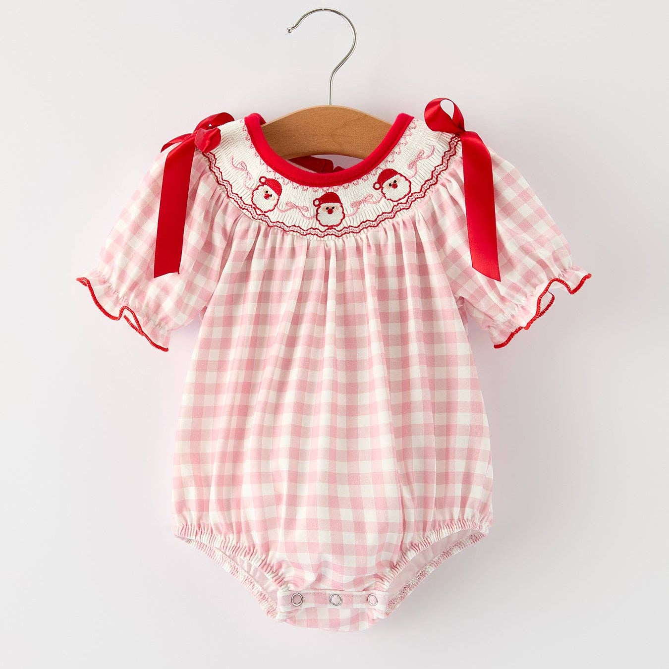 Pink checkered baby romper with red accents on a white background