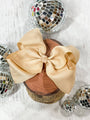 Large beige bow on a wooden block with disco balls around it