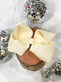 Wooden block with a large beige bow, surrounded by disco balls on a light background