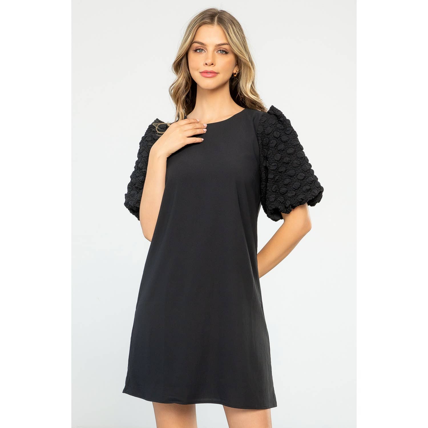 Woman wearing a black dress with textured sleeves on a white background
