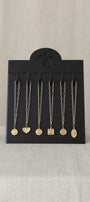 Black jewelry display card with hanging necklaces on a beige background
