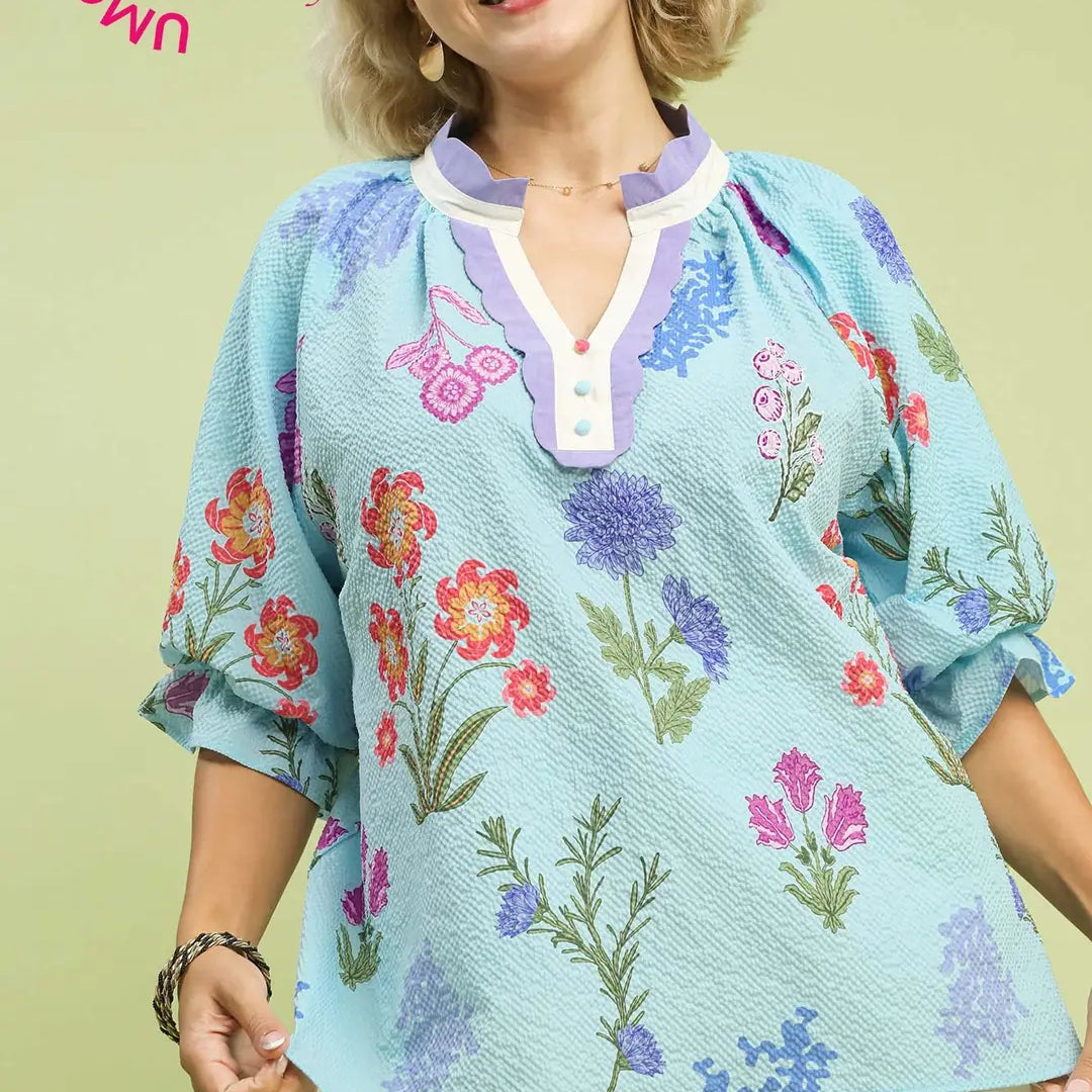 Woman wearing a floral embroidered blouse with a light green background