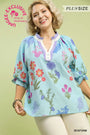 Woman wearing a floral embroidered blouse with a light green background