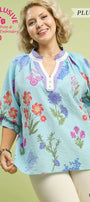 Woman wearing a floral embroidered blouse with a light green background