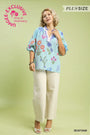 Woman wearing a floral blouse and beige pants on a light green background with 'UMgee Exclusive' branding.