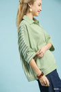 Woman wearing a green striped shirt against a light blue background