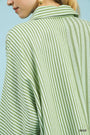 Green and white striped shirt worn by a person against a light blue background
