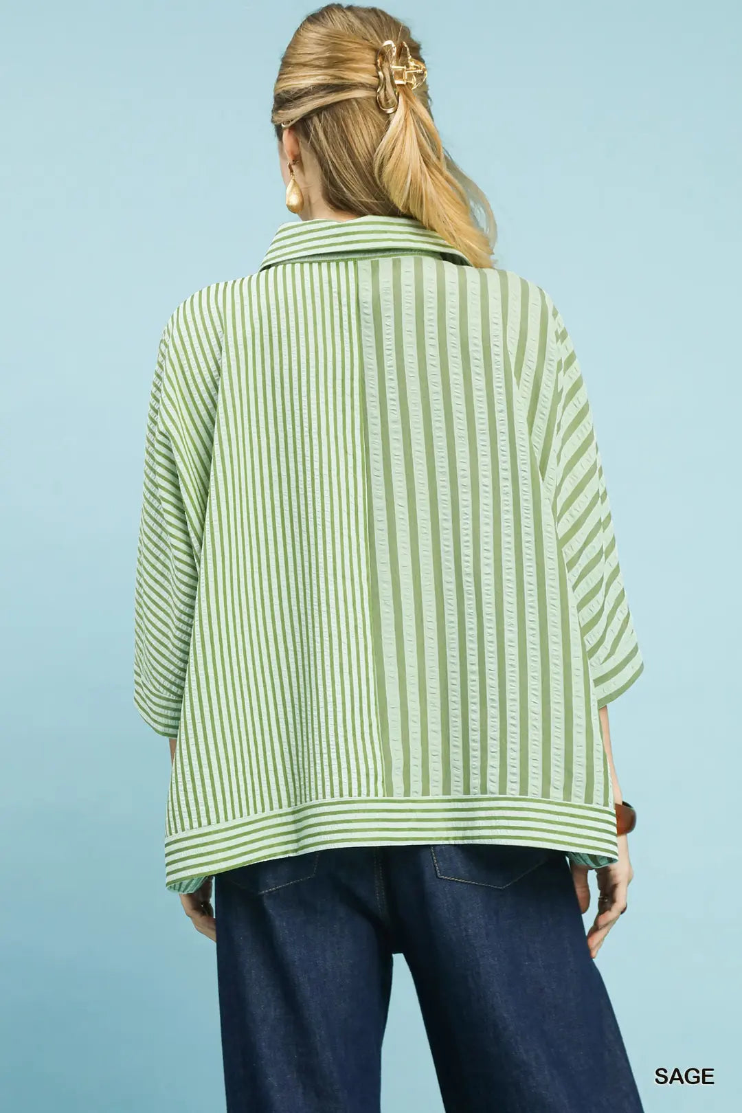 Person wearing a green and white striped shirt with blue pants on a light blue background