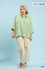 Woman wearing a green striped shirt and beige pants on a light blue background