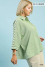 Woman wearing a green striped plus-size top against a light blue background