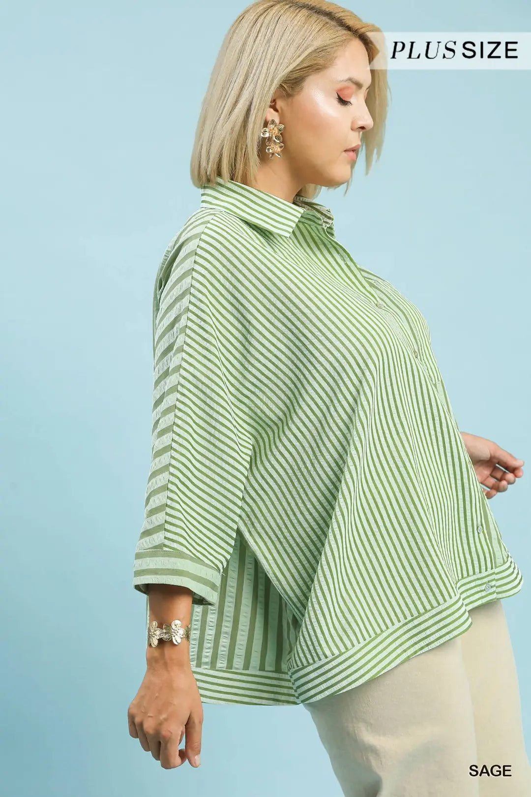 Woman wearing a green striped plus-size top against a light blue background