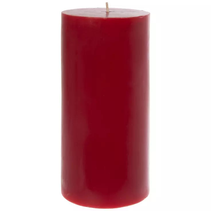A single tall, cylindrical red pillar candle with a visible wick, centered against a plain white background.