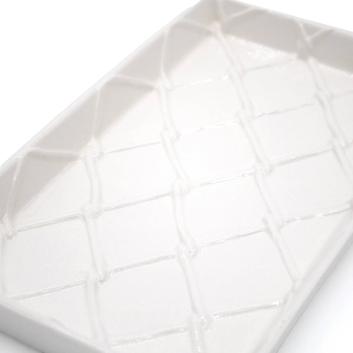 White ceramic guest towel tray with raised geometric grid texture, close-up