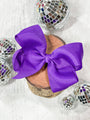 Purple bow on a wooden spool with disco balls in the background