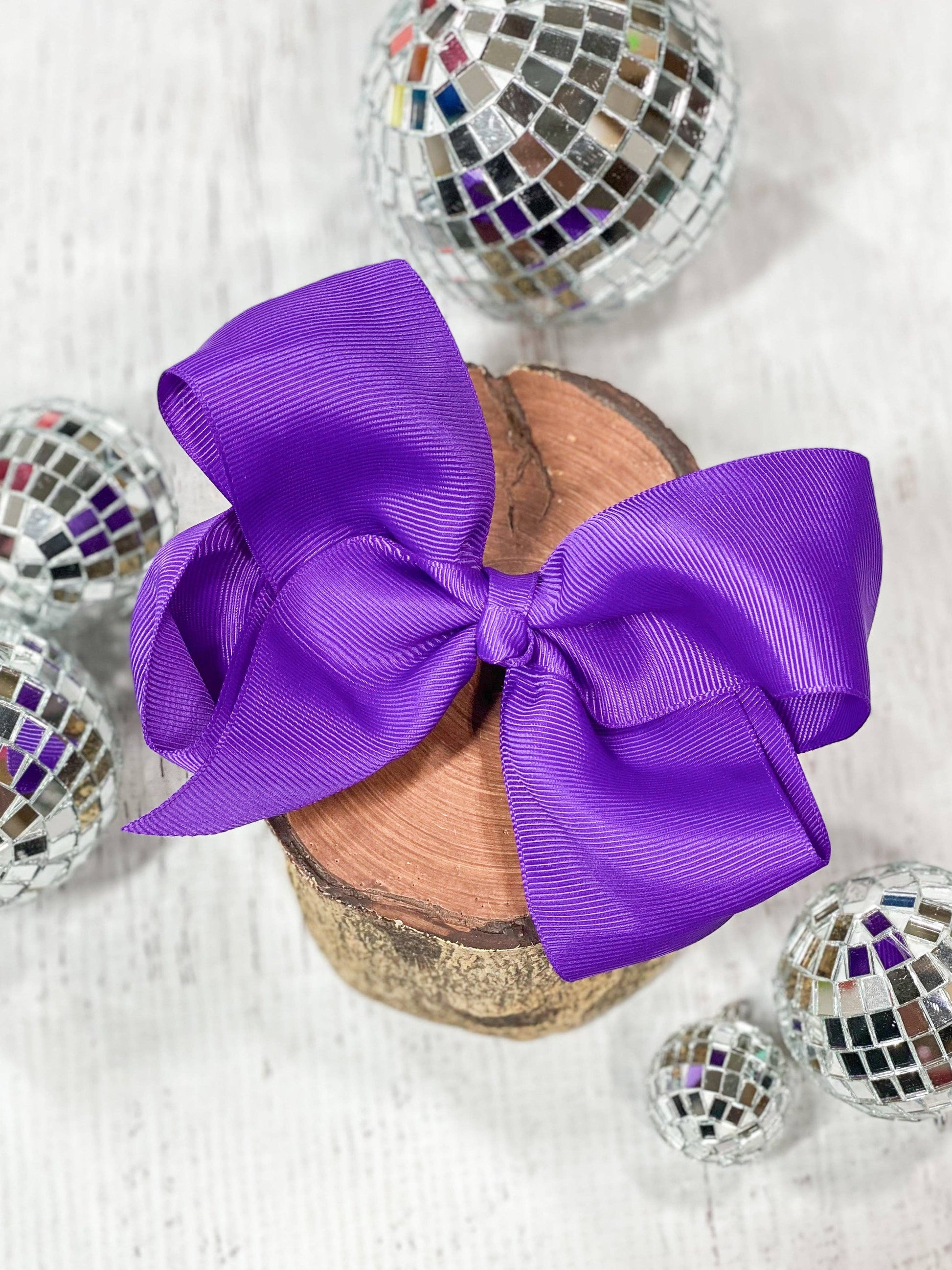 Purple bow on a wooden spool with disco balls in the background