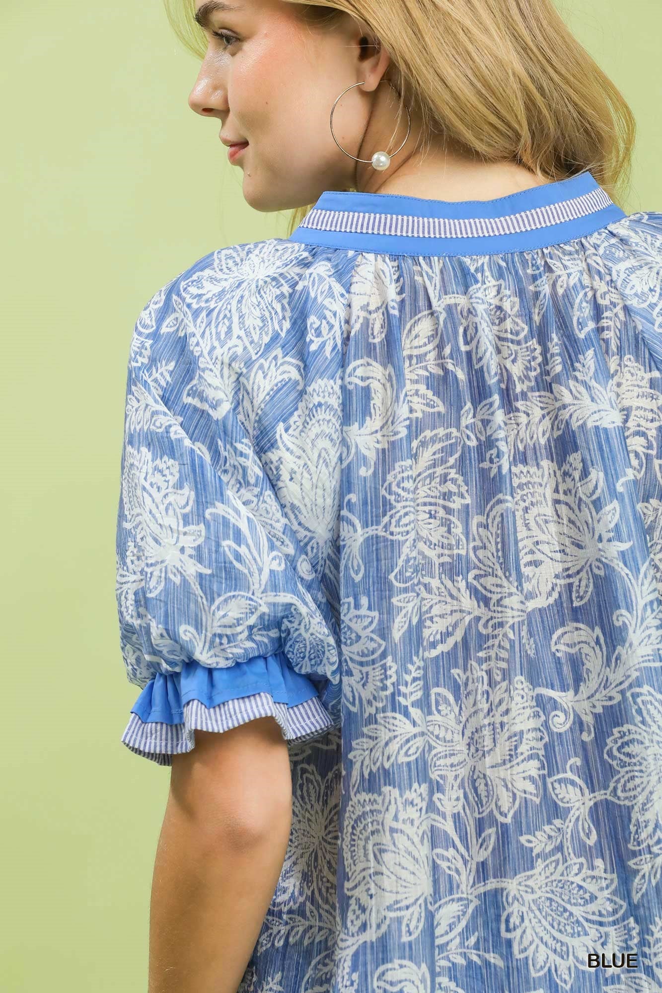 Woman wearing a blue and white patterned dress with a green background