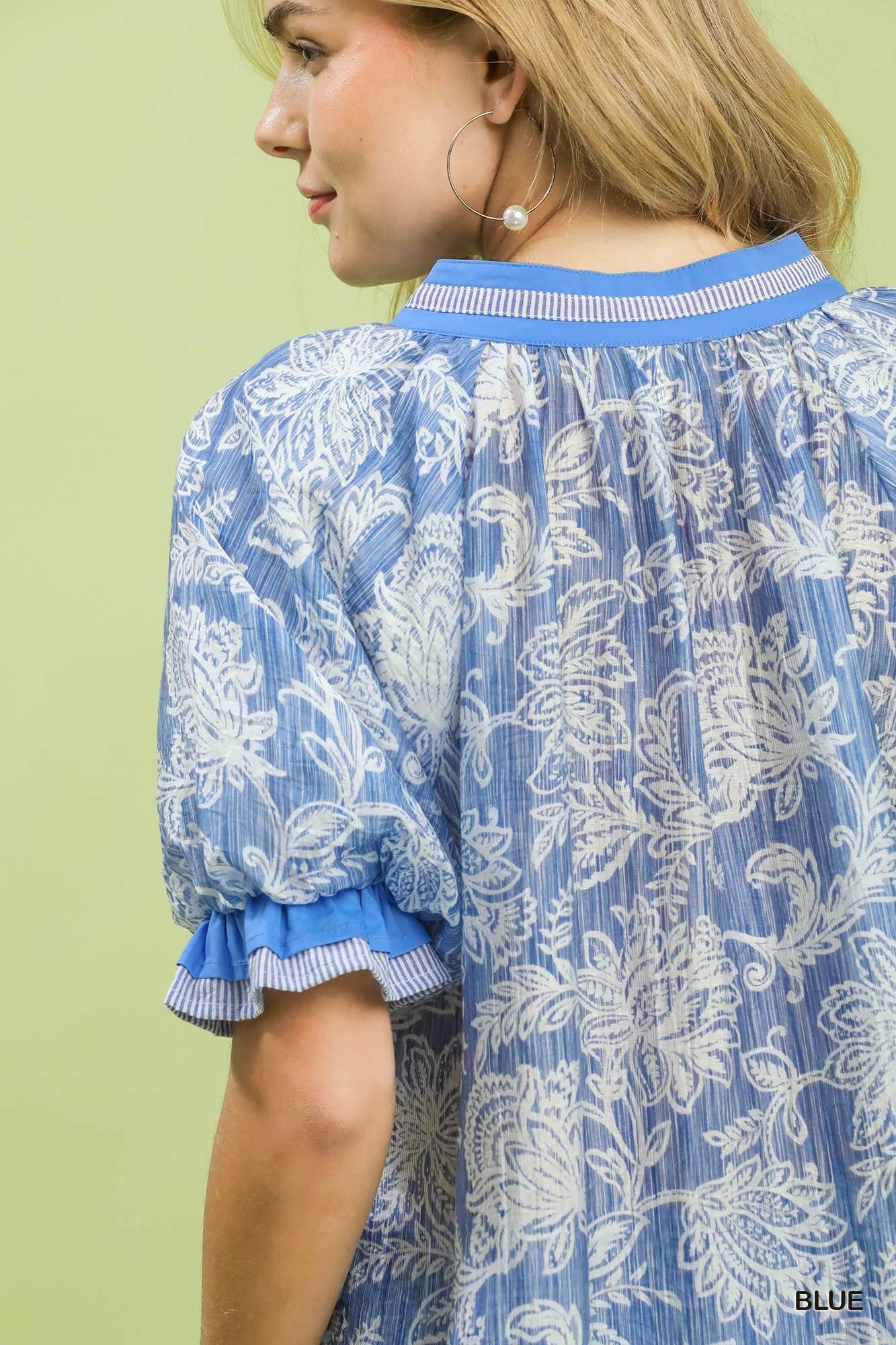 Woman wearing a blue and white patterned dress with a green background