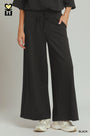 Person wearing black wide-leg pants with a plain background