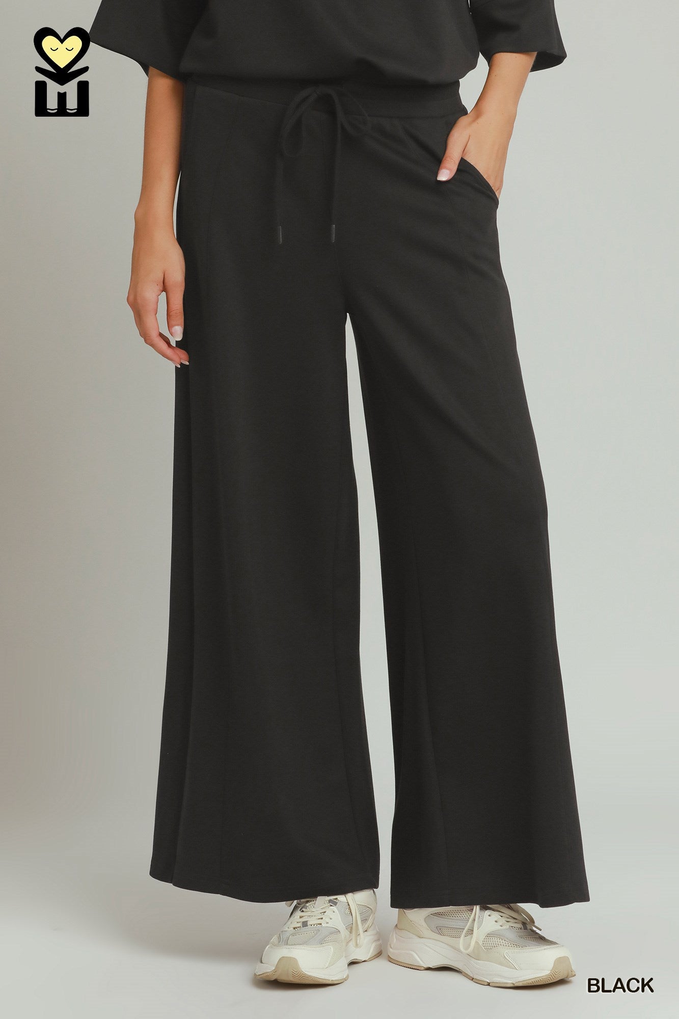 Person wearing black wide-leg pants with a plain background