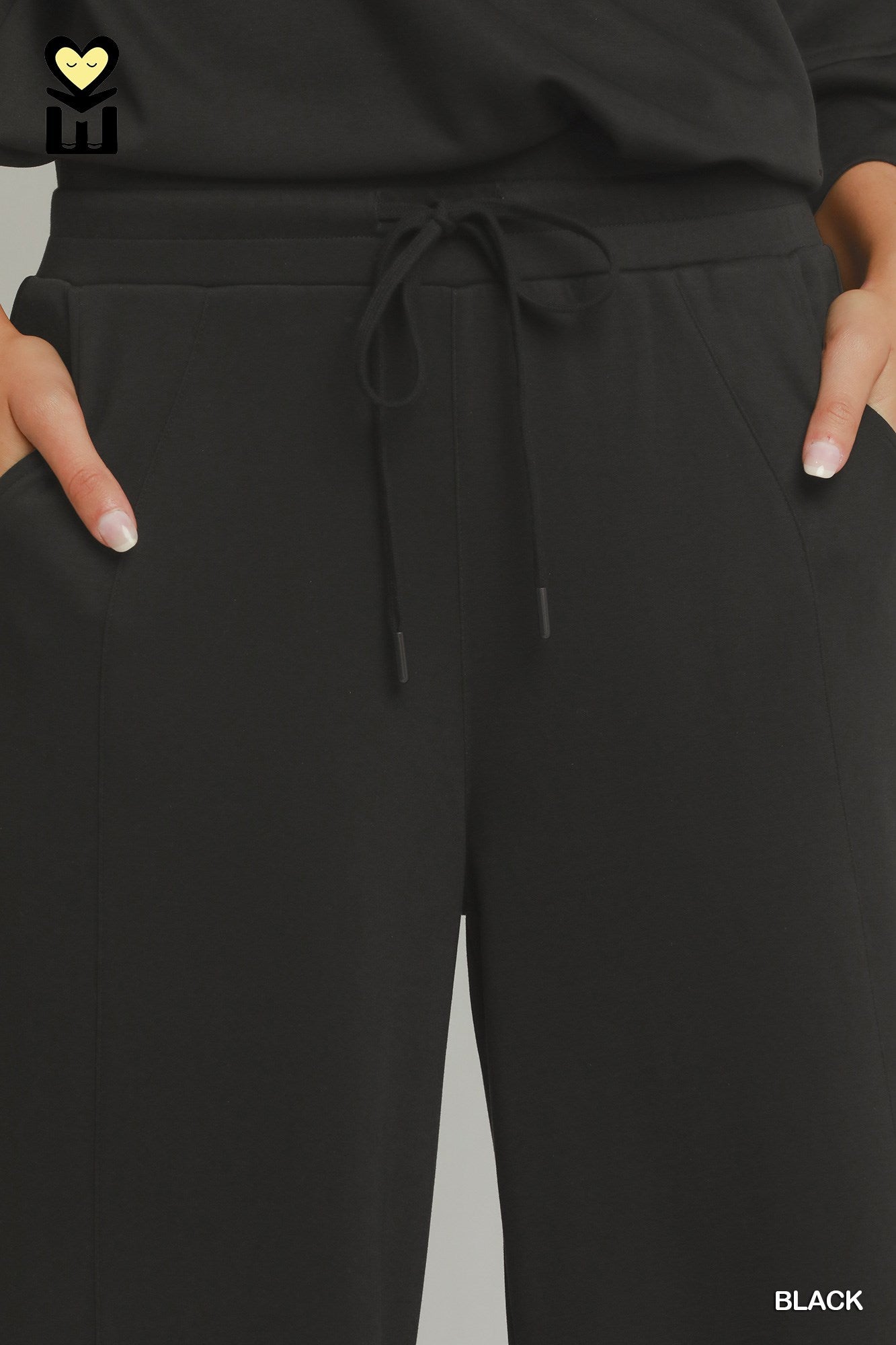 Black pants with a drawstring waist on a gray background