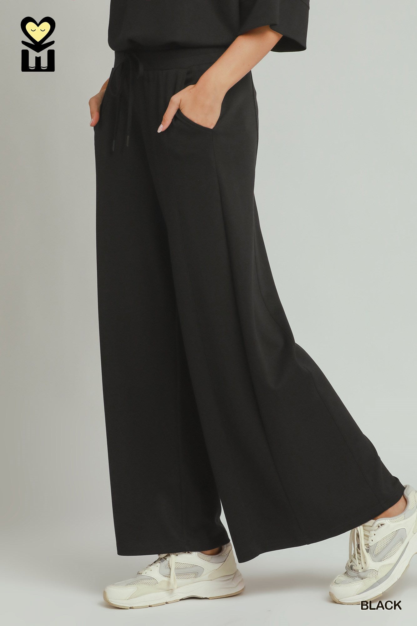 Person wearing black wide-leg pants with a neutral background