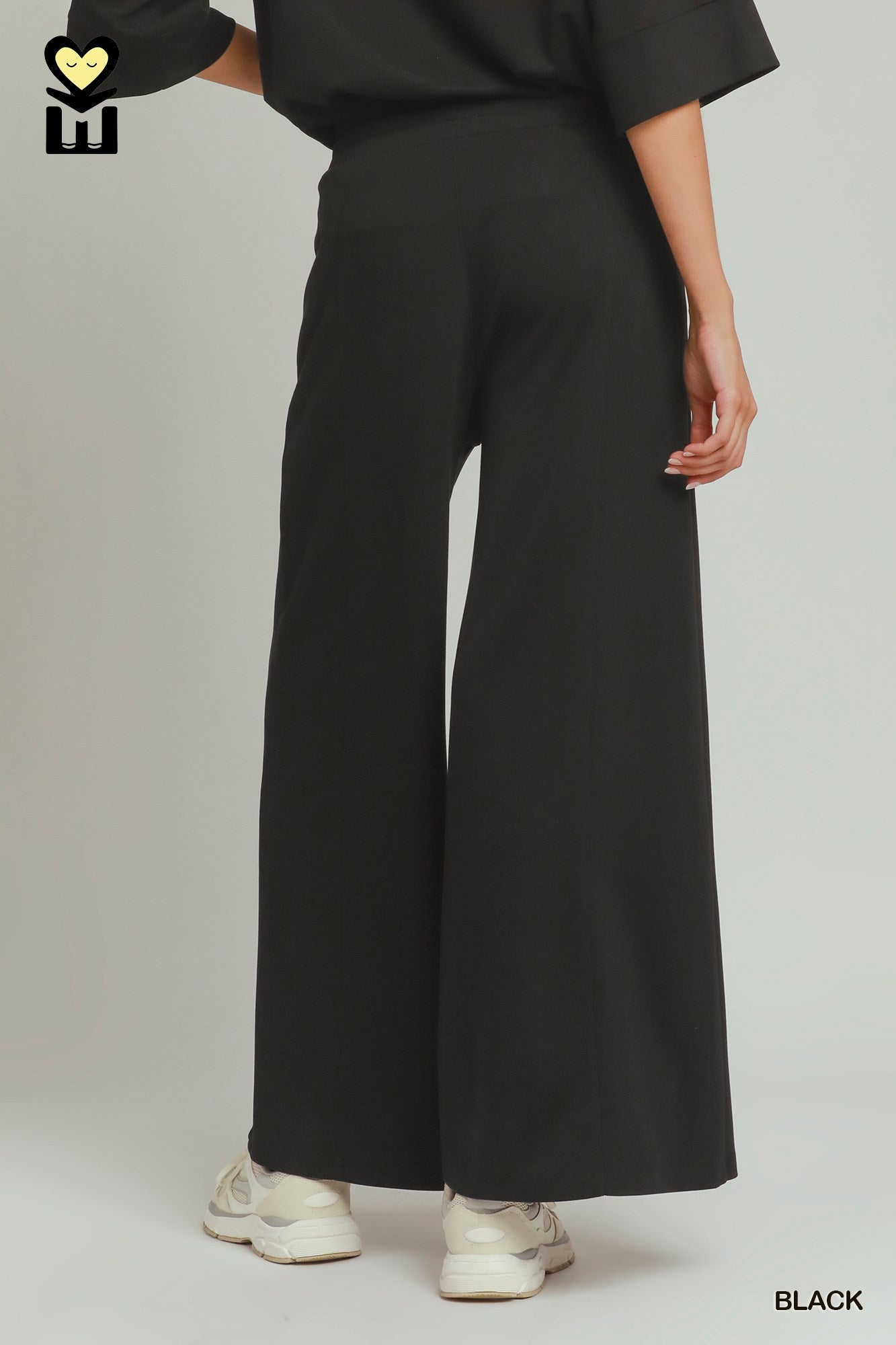 Person wearing black wide-leg pants on a plain background