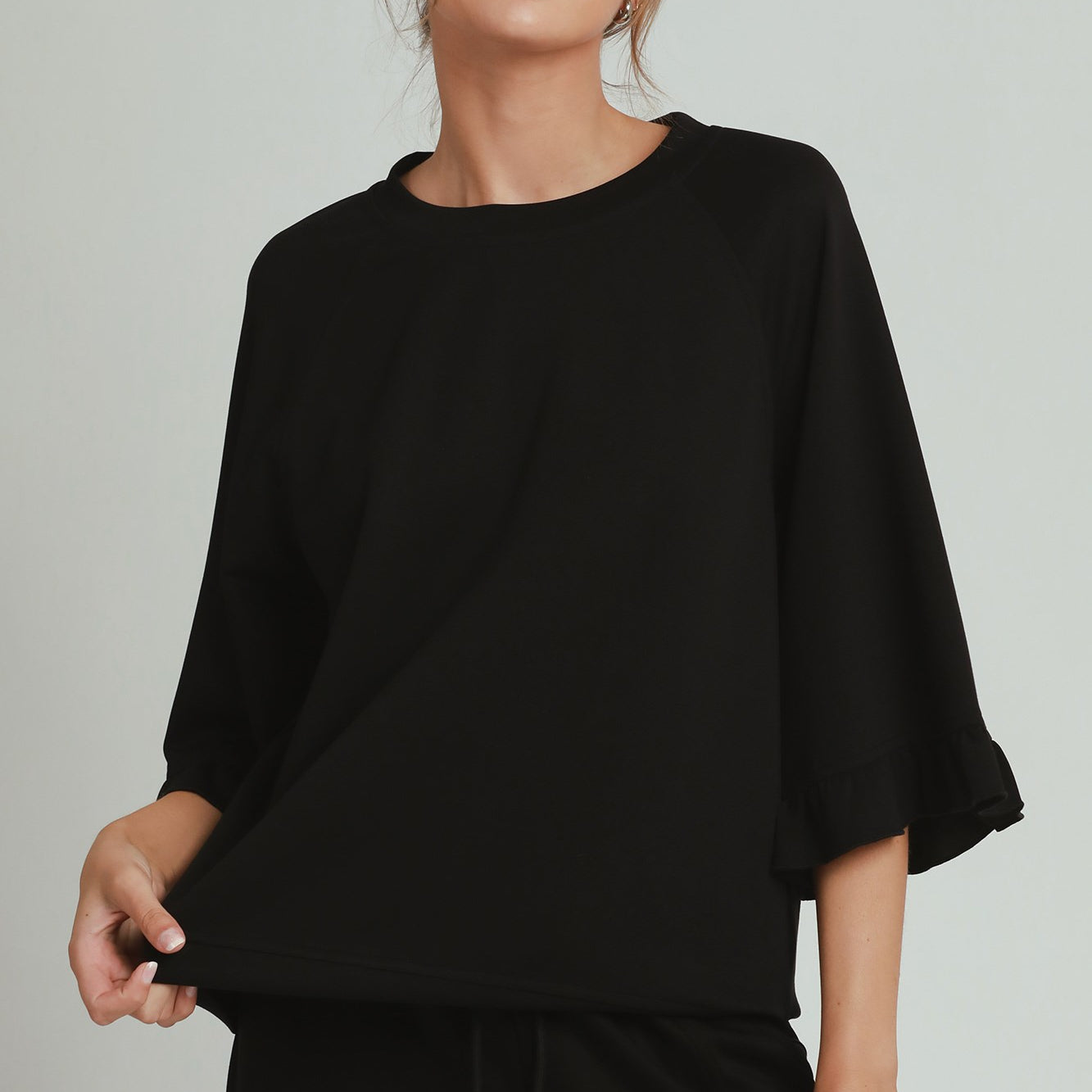 Woman wearing a black outfit with sunglasses on a plain background