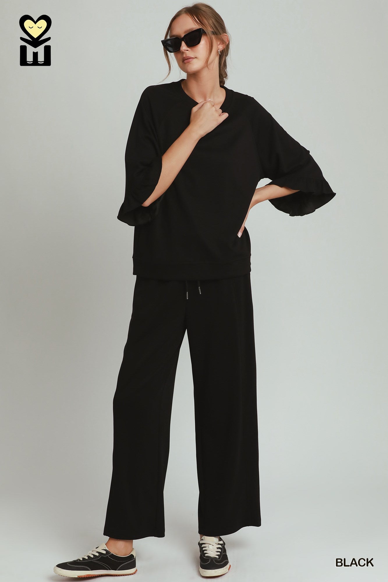 Person wearing a black outfit with sunglasses on a white background