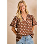 Woman wearing a brown polka dot blouse and blue jeans against a beige background