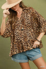 Woman wearing a leopard print top and denim shorts against a green background