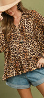 Woman wearing a leopard print top and denim shorts against a green background