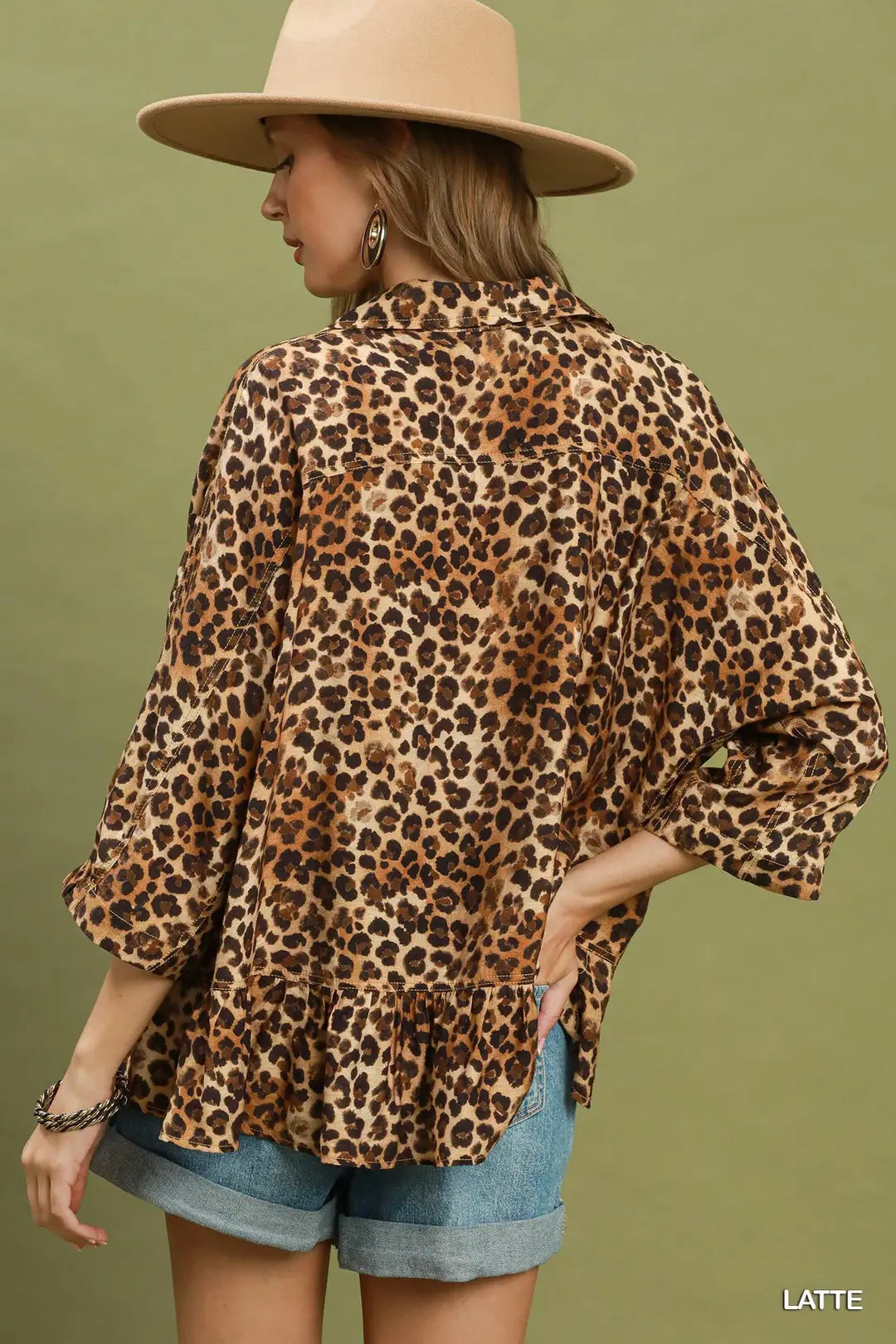 Person wearing a leopard print blouse and beige hat on a green background