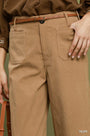 A close-up of a person wearing taupe wide-leg trousers with a brown belt, a brown textured top, and a hand resting on the pocket. The color 'TAUPE' is printed in the bottom right corner.